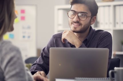 Man on computer talking to colleague
