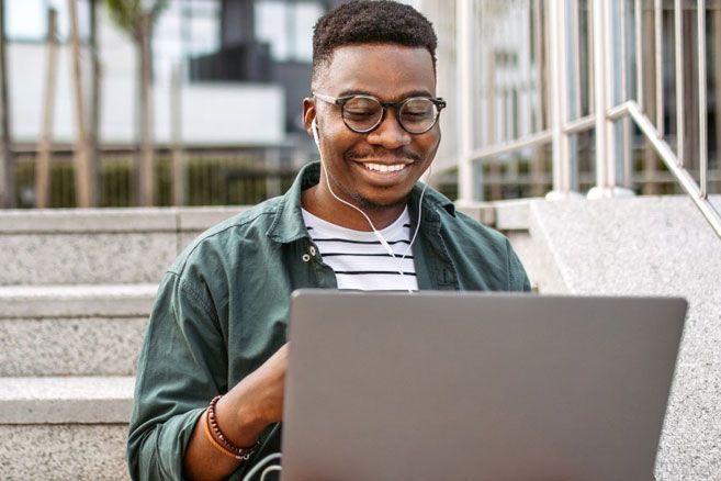 Man works on laptop outdoors on stairs